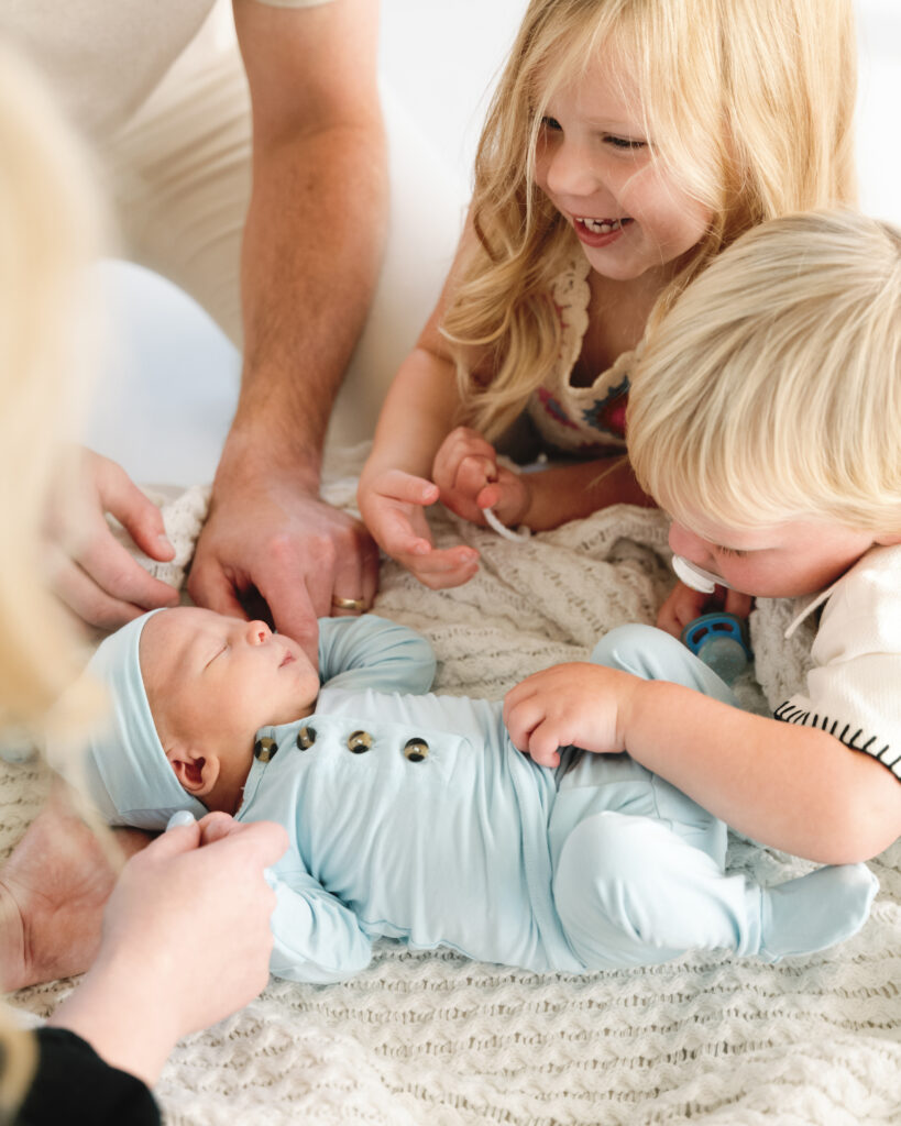Children snuggled with new sibling during a relaxed family portrait session